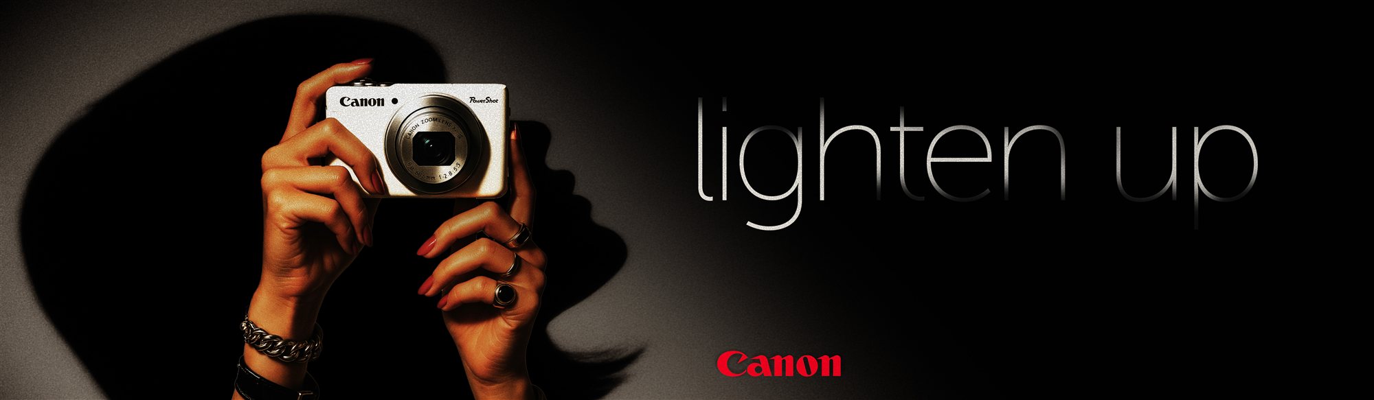 Lighten Up print ad: hands holding a Canon PowerShot in a beam of light, with the headline “lighten up”.